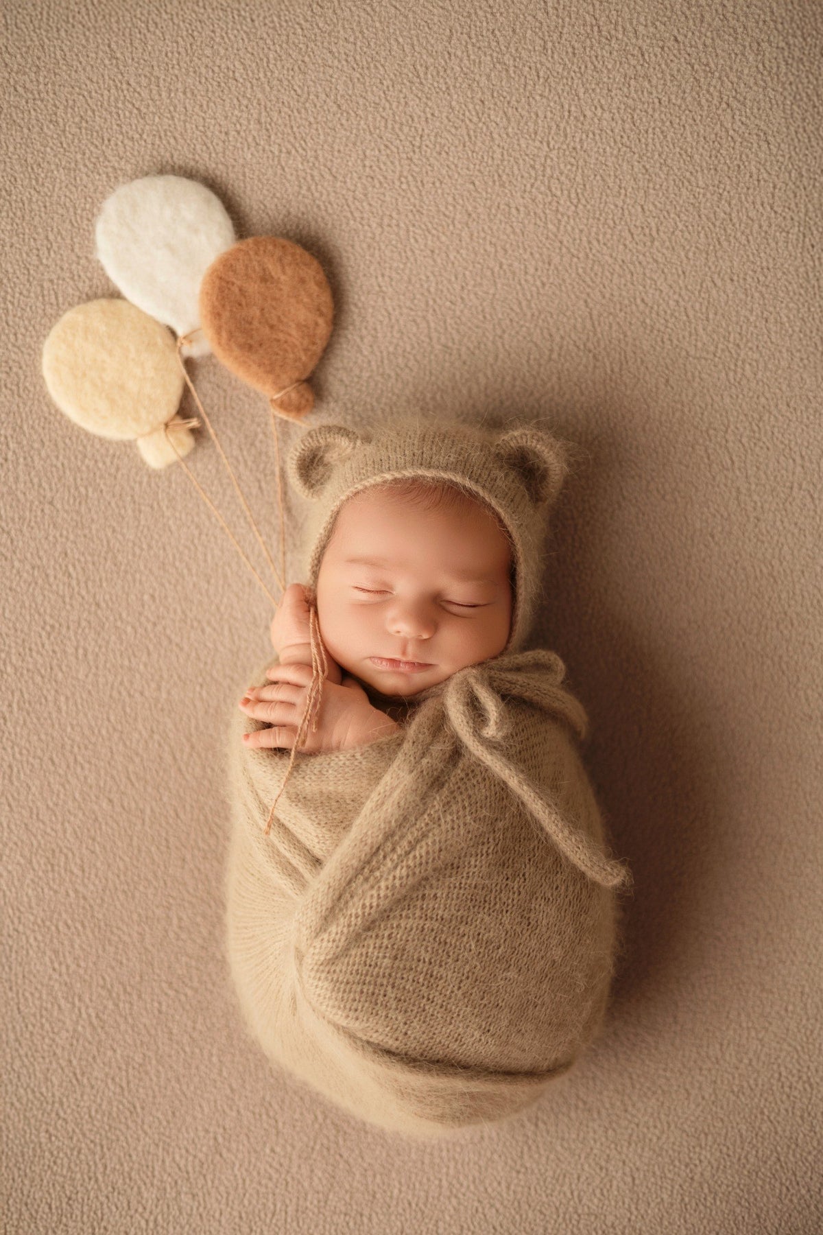 Bébé endormi emmailloté dans un décor beige avec accessoires