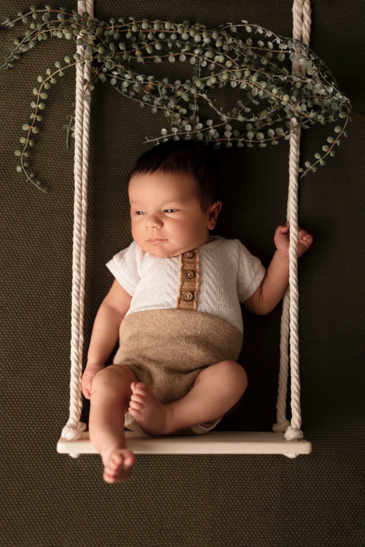 Bébé photographié sur une petite balançoire lors d’une séance Naissance