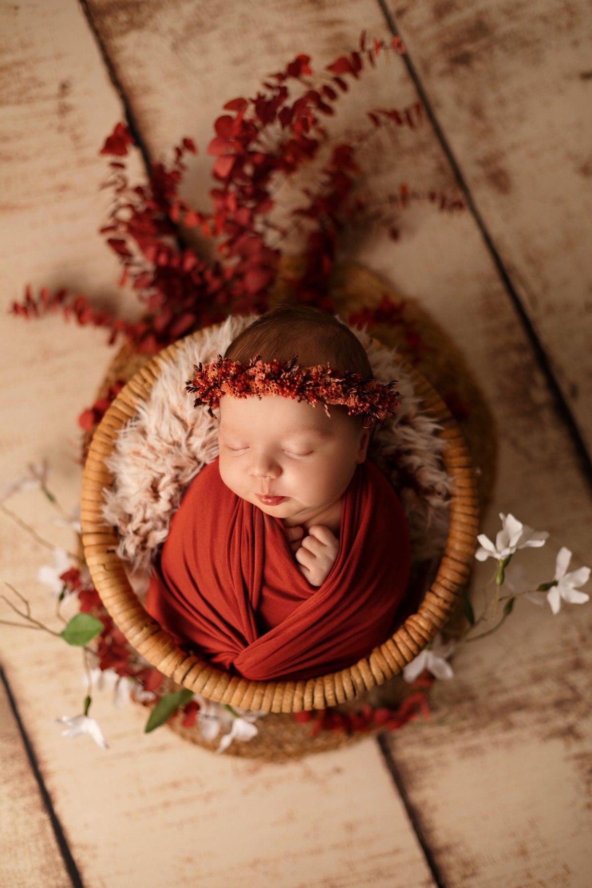Nouveau-né endormi emmailloté dans un décor terracotta – séance Naissance