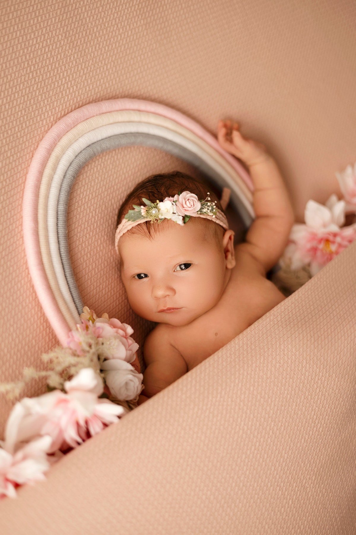 Bébé photographié dans un décor rose fleuri lors d’une séance Naissance