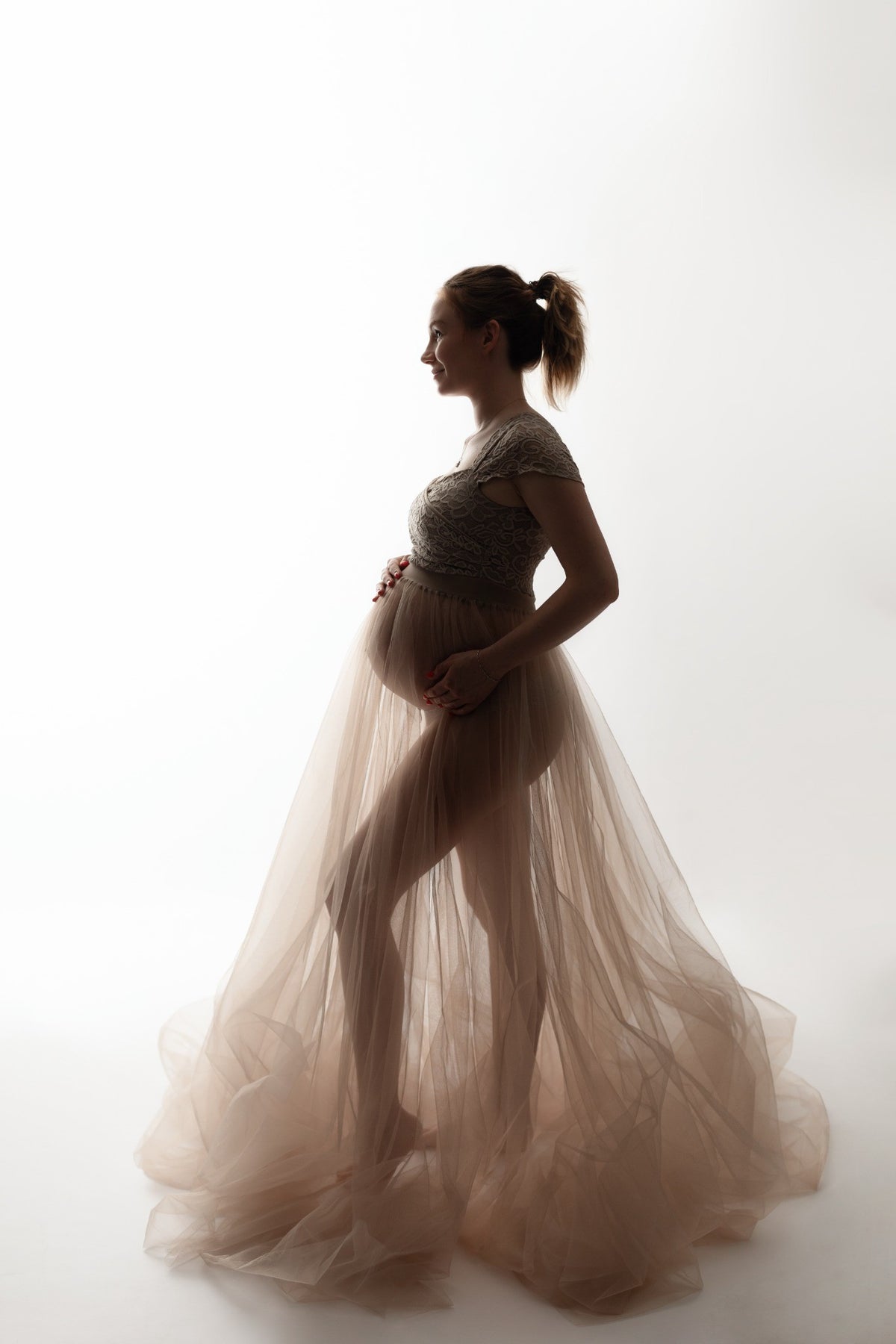 Silhouette d'une femme enceinte en robe blanche et lumière naturelle