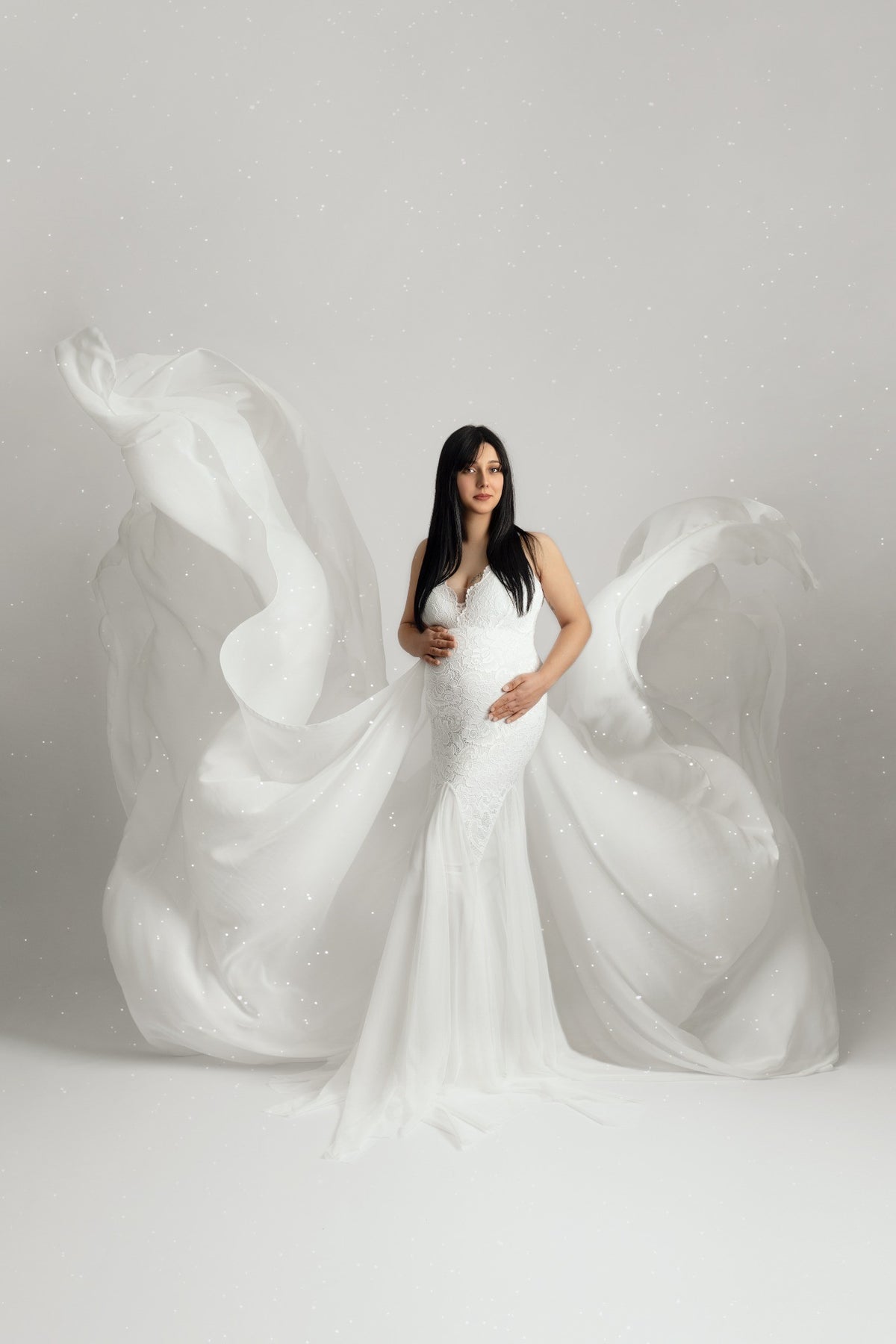 Portrait de grossesse élégant en robe blanche avec voilages