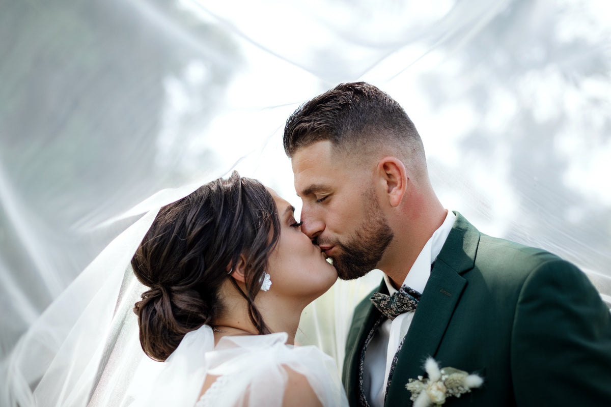 Baiser des mariés sous le voile de la mariée