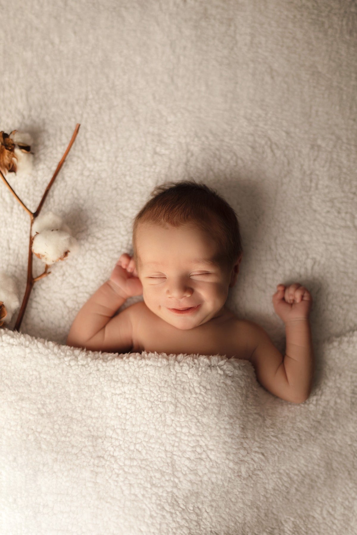 Bébé souriant allongé sur une couverture blanche au studio