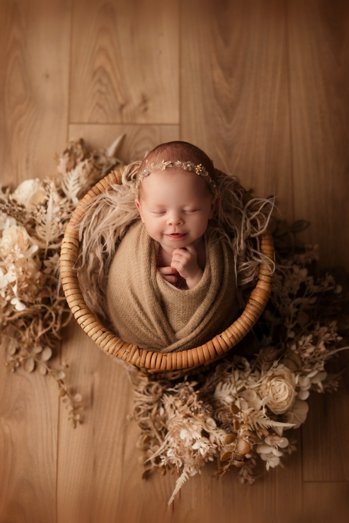 Bébé emmailloté dans un panier entouré de fleurs séchées