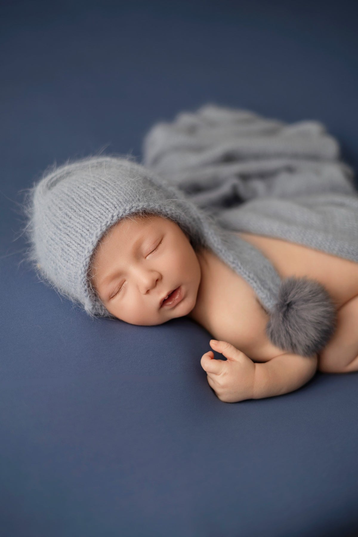 Nouveau-né endormi avec bonnet bleu sur fond bleu