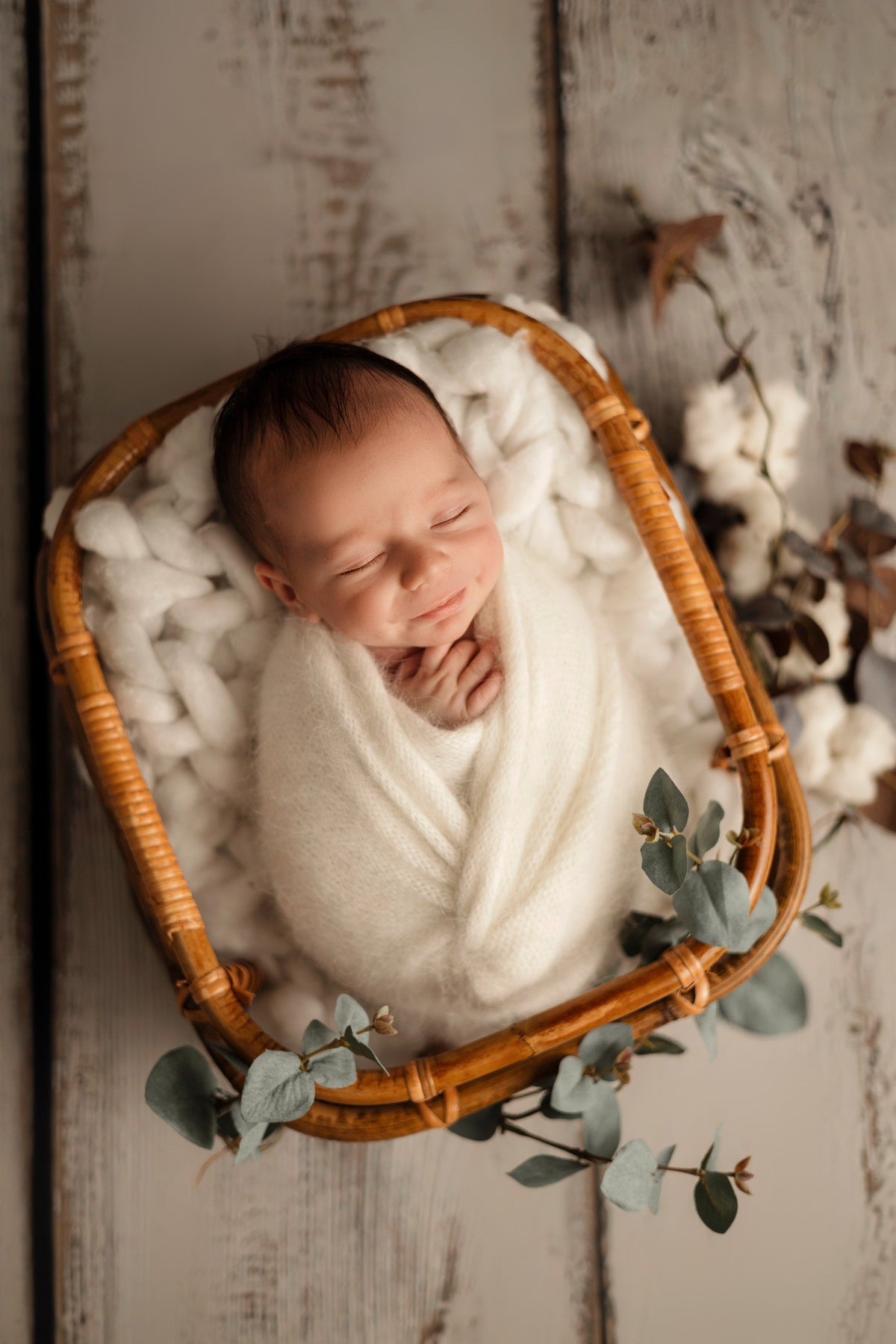 Bébé endormi dans un panier en osier et décor blanc naturel