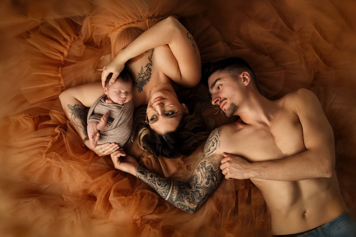 Parents allongés avec leur nouveau-né lors d’une séance photo Naissance