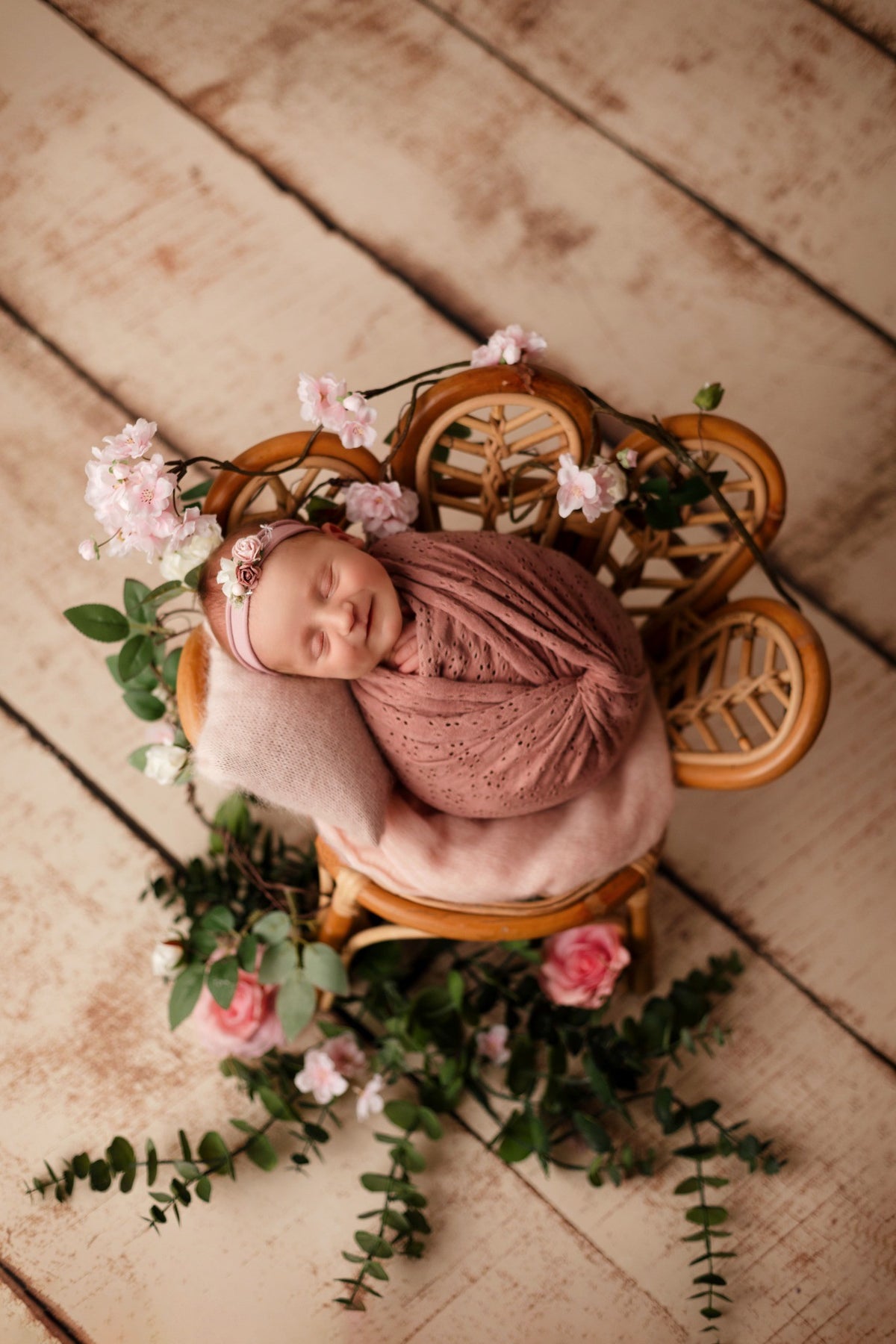 Nouveau-né emmailloté dans un décor rose fleuri avec petit lit