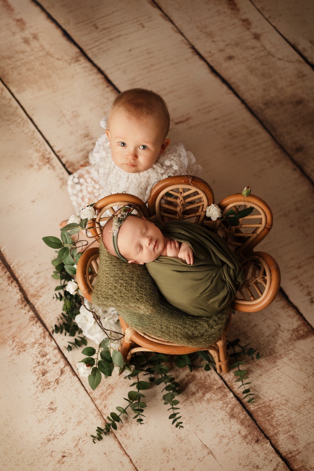 Bébé et nouveau-né photographiés ensemble dans un décor végétal