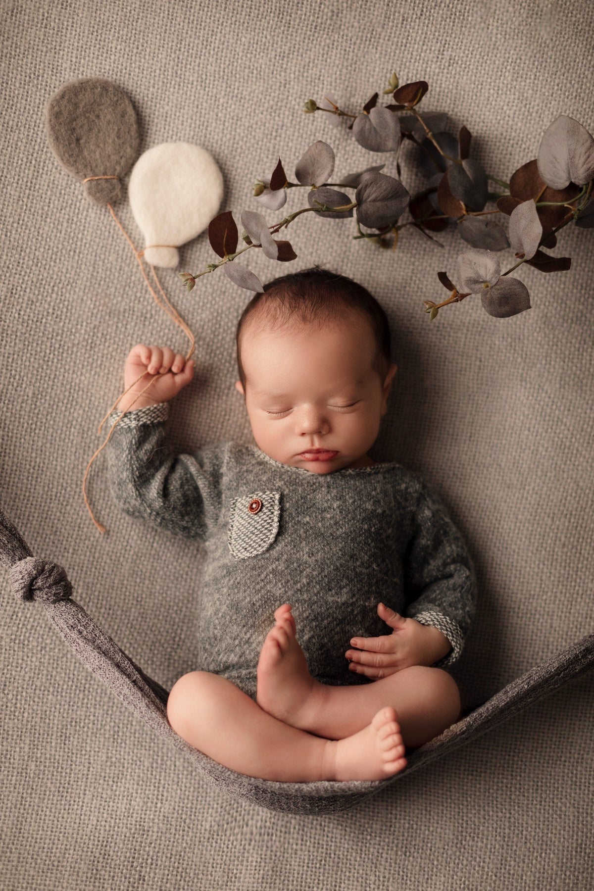 Nouveau-né endormi dans une mise en scène naturelle avec eucalyptus