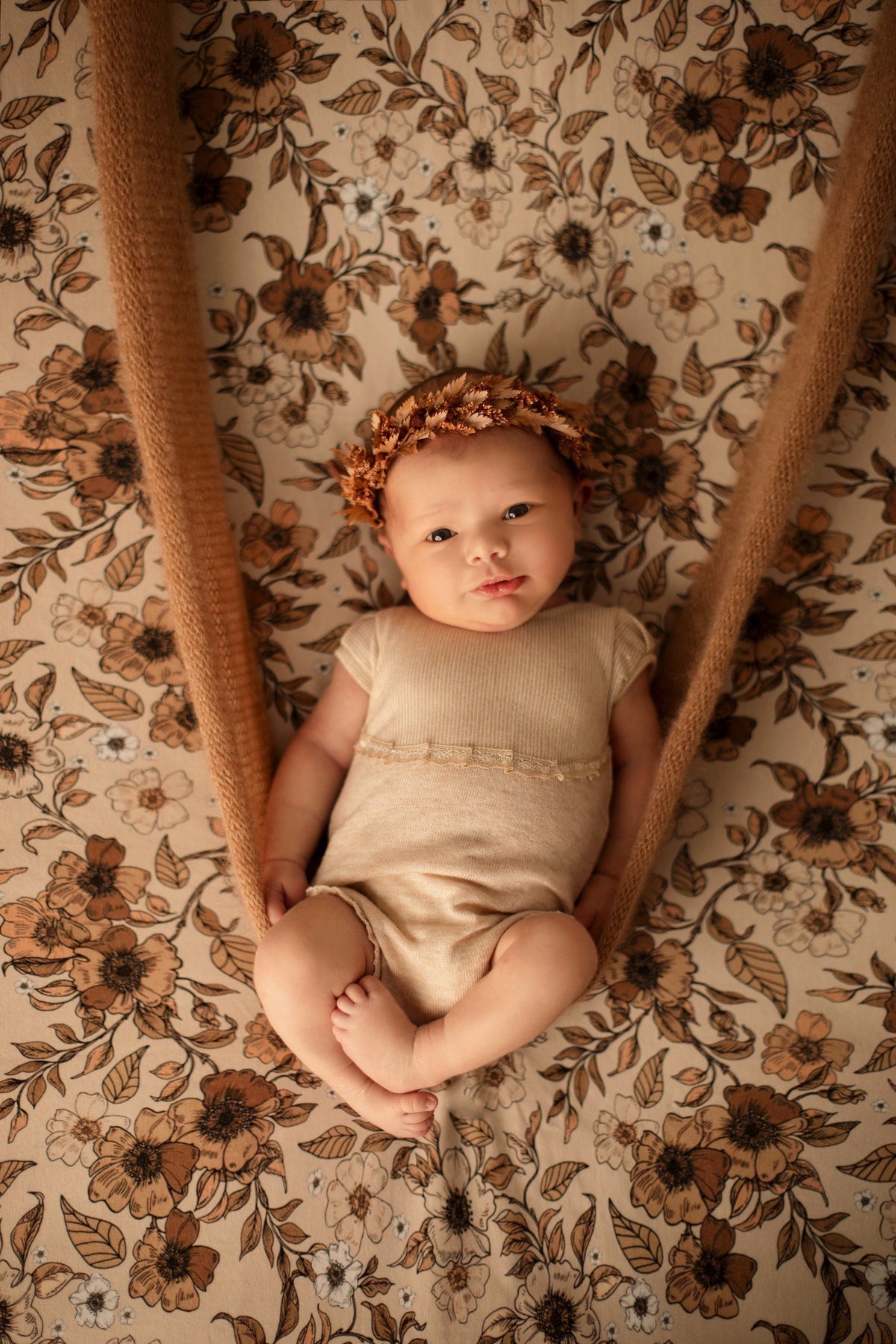Bébé photographié dans un décor floral aux tons beige et terracotta